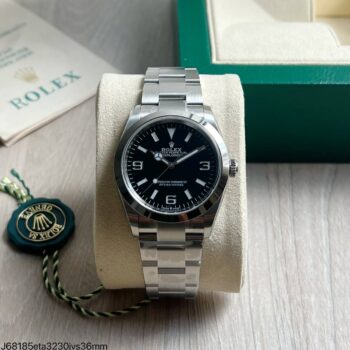 Super clone Rolex Explorer I 124270 36mm mostrador preto em aço com pulseira Oyster sobre almofada bege com box verde Rolex ao fundo