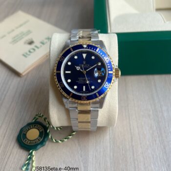 Super clone Rolex Submariner Date 16613 two-tone aço e ouro amarelo com mostrador azul sunburst e bezel cerâmico azul, 40mm, sobre almofada de apresentação com caixa verde Rolex ao fundo