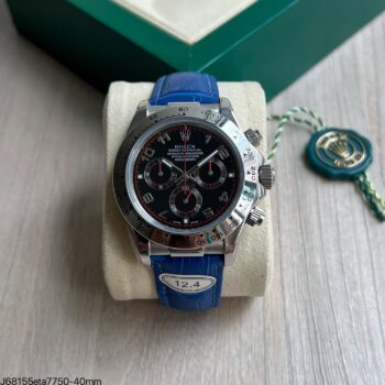 Super clone Rolex Cosmograph Daytona ETA 7750 com mostrador preto, detalhes vermelhos e pulseira em couro azul crocodilo, 40mm, sobre almofada de exposição com caixa verde Rolex ao fundo