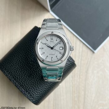 Super clone IWC Ingenieur Automatic 41mm com mostrador prata texturizado quadriculado e bracelete integrado em aço, apoiado sobre carteira de couro preta